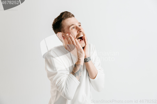 Image of The happy businessman standing and smiling against gray background.