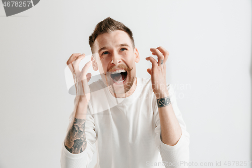 Image of The young emotional angry man screaming on garay studio background