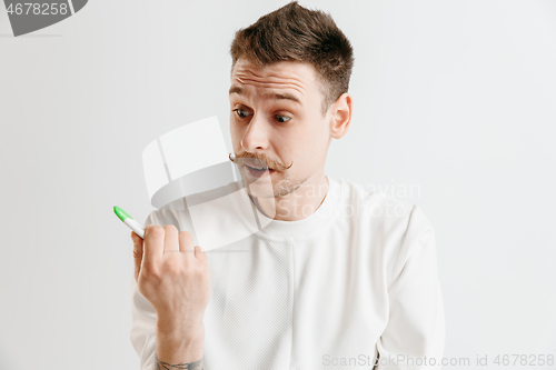 Image of Upset man looking in pregnancy test. Frustrated model