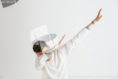 Image of Young man makes the dab movement with his arms on a gray background.