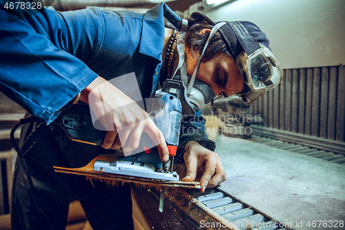 Image of Carpenter using circular saw for cutting wooden boards.