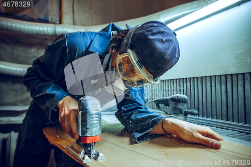 Image of Carpenter using circular saw for cutting wooden boards.