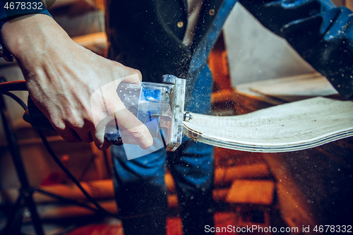 Image of Carpenter using circular saw for cutting wooden boards.