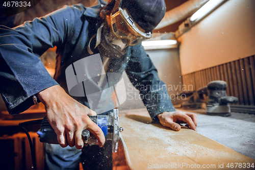 Image of Carpenter using circular saw for cutting wooden boards.