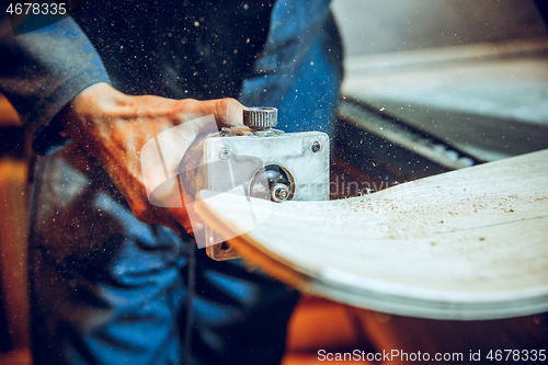 Image of Carpenter using circular saw for cutting wooden boards.