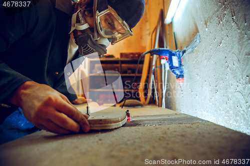 Image of Portrait of handsome carpenter working with skate at workshop