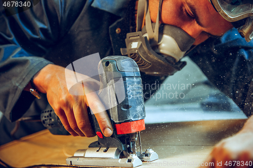 Image of Carpenter using circular saw for cutting wooden boards.