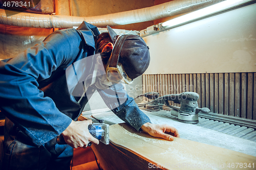 Image of Carpenter using circular saw for cutting wooden boards.