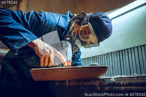 Image of Carpenter using circular saw for cutting wooden boards.