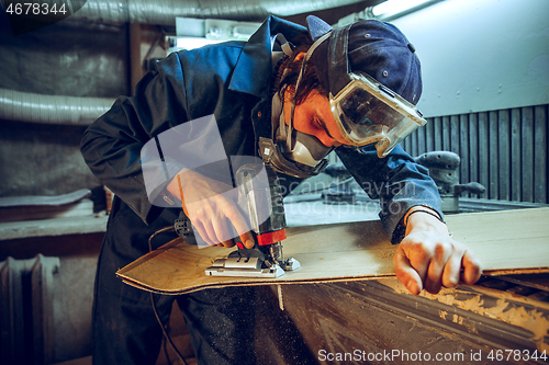 Image of Carpenter using circular saw for cutting wooden boards.