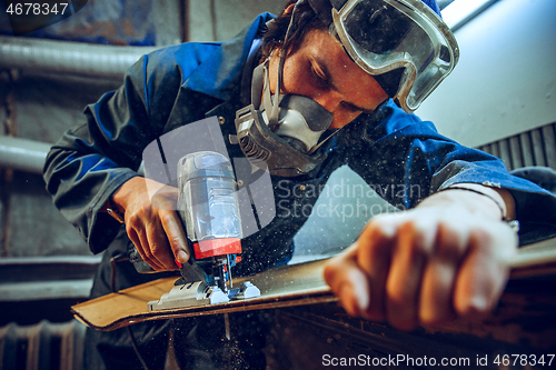 Image of Carpenter using circular saw for cutting wooden boards.