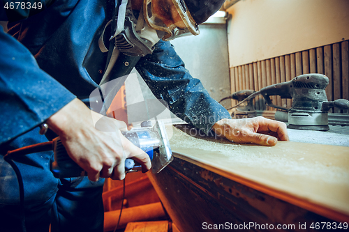 Image of Carpenter using circular saw for cutting wooden boards.