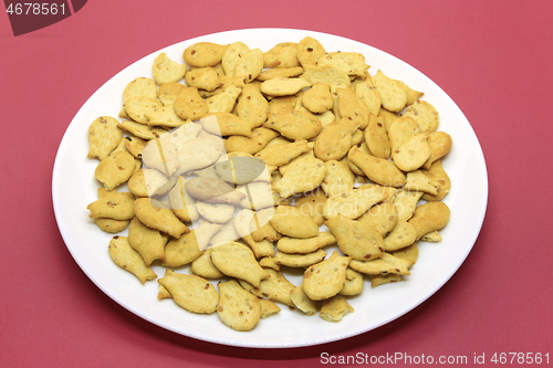 Image of Fish-shaped cookies in a white plate on a crimson background 