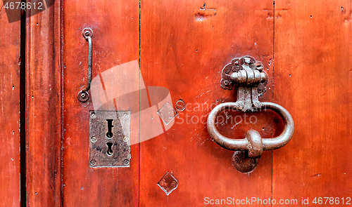 Image of Vintage red wooden door with metallic doorhandle and keyholes