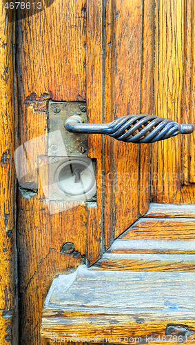 Image of Vintage yellow wooden door with decorative handle and keyhole