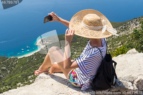 Image of Active sporty woman on summer vacations taking selfie picture while enjoying beautiful coastal view of Cres island, Croatia from Lubenice traditional costal village