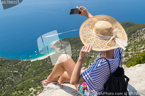 Image of Active sporty woman on summer vacations taking selfie picture while enjoying beautiful coastal view of Cres island, Croatia from Lubenice traditional costal village