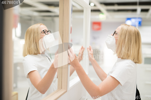 Image of New normal during covid epidemic. Caucasian woman shopping at retail furniture and home accessories store wearing protective medical face mask to prevent spreading of corona virus