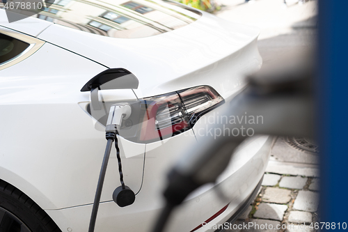 Image of Power supply for electric car charging. Electric car charging station. Close up of the power supply plugged into an electric car being charged