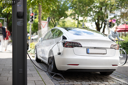 Image of Electric car getting charged at special parking spot with an electric battery charging station.