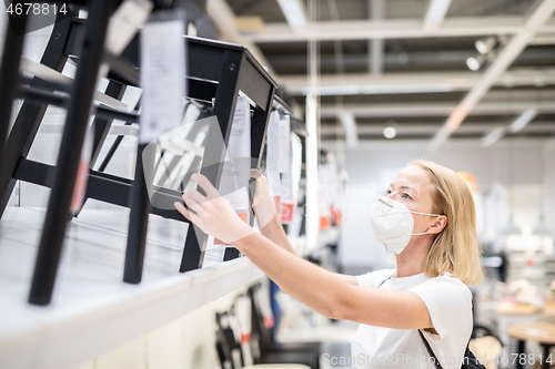 Image of New normal during covid epidemic. Caucasian woman shopping at retail furniture and home accessories store wearing protective medical face mask to prevent spreading of corona virus