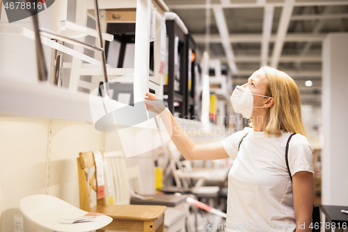 Image of New normal during covid epidemic. Caucasian woman shopping at retail furniture and home accessories store wearing protective medical face mask to prevent spreading of corona virus