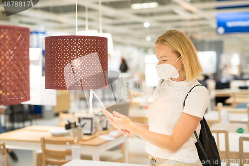 Image of New normal during covid epidemic. Caucasian woman shopping at retail furniture and home accessories store wearing protective medical face mask to prevent spreading of corona virus