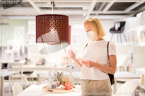 Image of New normal during covid epidemic. Caucasian woman shopping at retail furniture and home accessories store wearing protective medical face mask to prevent spreading of corona virus