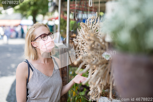 Image of Casual woman shopping outdoor at open market stalls wearing fase masks for protection from corona virus pandemic in Munchen, Germany