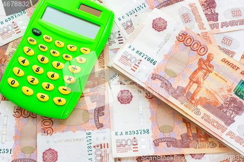 Image of Against the background of money is a calculator and a pack of five thousandth Russian rubles