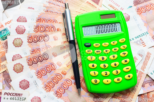 Image of A calculator with the number one million and a ballpoint pen lie against the background of Russian five-thousandth bills