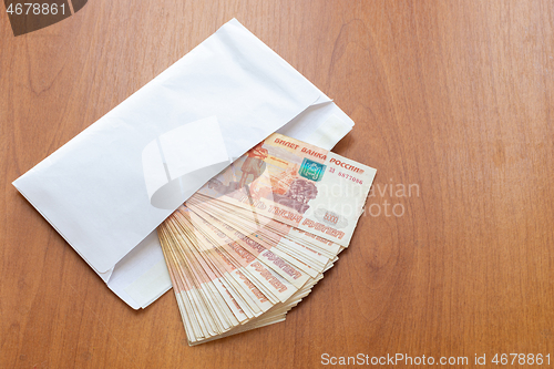 Image of There is a bundle of money in an envelope on the table