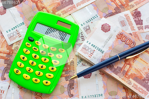 Image of The number 1,000,000 is written on the calculator, the calculator and the ballpoint pen lie on a pile of money