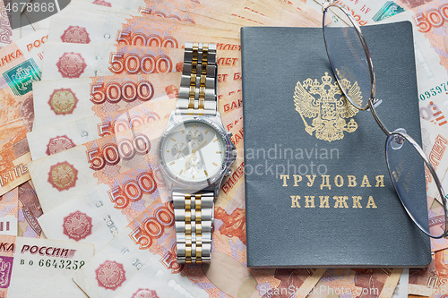 Image of On a pack of five thousandth bills there is a work book, a watch and glasses