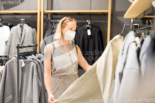 Image of Fashionable woman wearing protective face mask shopping clothes in reopen retail shopping store. New normal lifestyle during corona virus pandemic