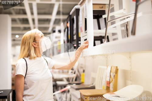 Image of New normal during covid epidemic. Caucasian woman shopping at retail furniture and home accessories store wearing protective medical face mask to prevent spreading of corona virus