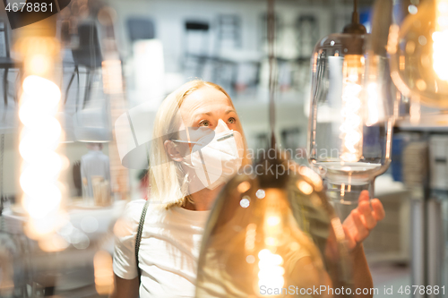 Image of New normal during covid epidemic. Caucasian woman shopping at retail furniture and home accessories store wearing protective medical face mask to prevent spreading of corona virus