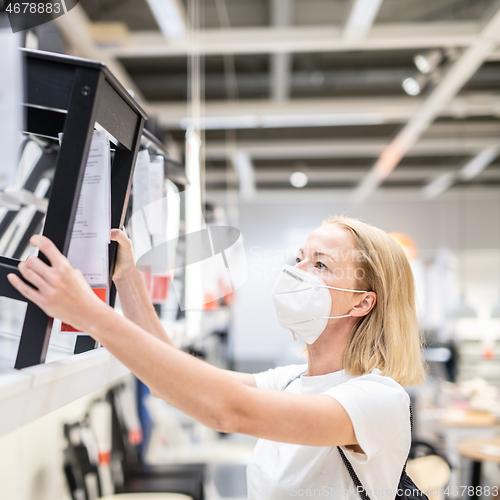 Image of New normal during covid epidemic. Caucasian woman shopping at retail furniture and home accessories store wearing protective medical face mask to prevent spreading of corona virus