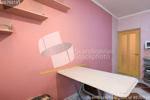 Image of Fragment of kitchen interior, dining table and part of a painted wall with shelves