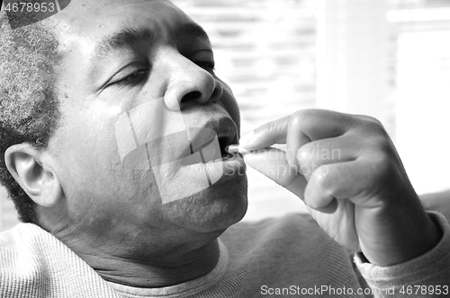 Image of Man taking his medications.