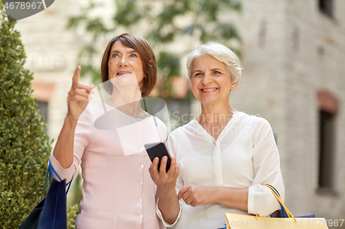 Image of old women with shopping bags and cellphone in city