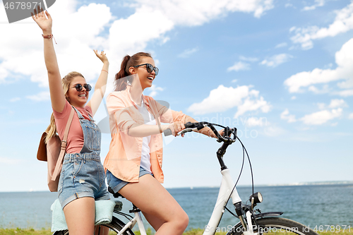 Image of teenage girls or friends riding bicycle in summer