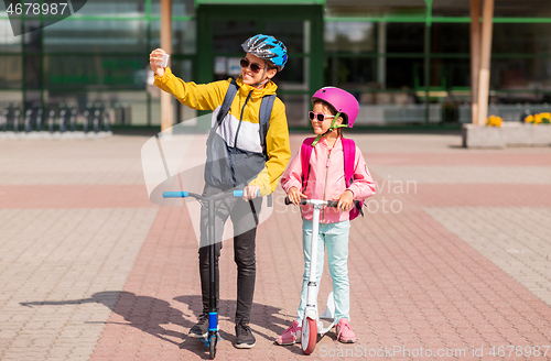 Image of happy school kids with scooters taking selfie