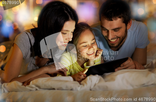 Image of family with tablet pc in bed at night at home