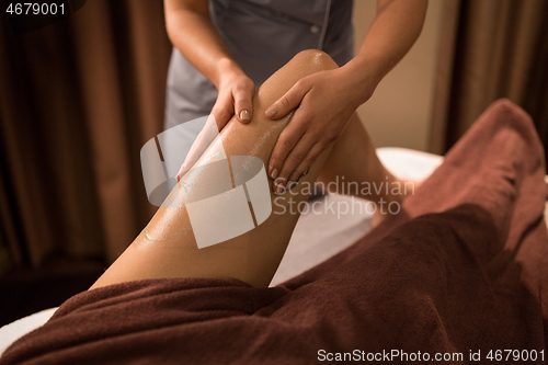 Image of woman lying and having leg massage with gel at spa