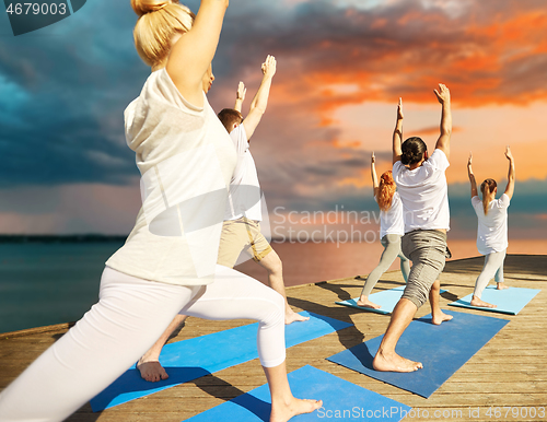 Image of group of people making yoga exercises outdoors