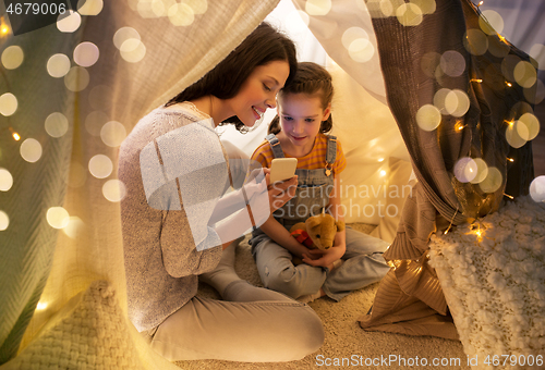 Image of happy family with smartphone in kids tent at home