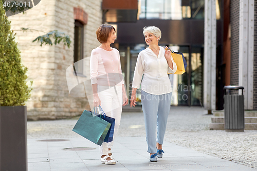 Image of senior women with shopping bags walking in city