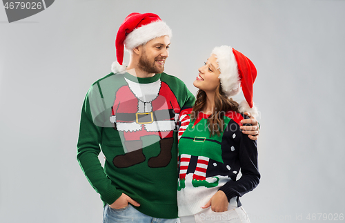 Image of happy couple in christmas sweaters and santa hats