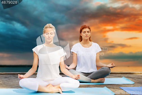 Image of women meditating in yoga lotus pose outdoors